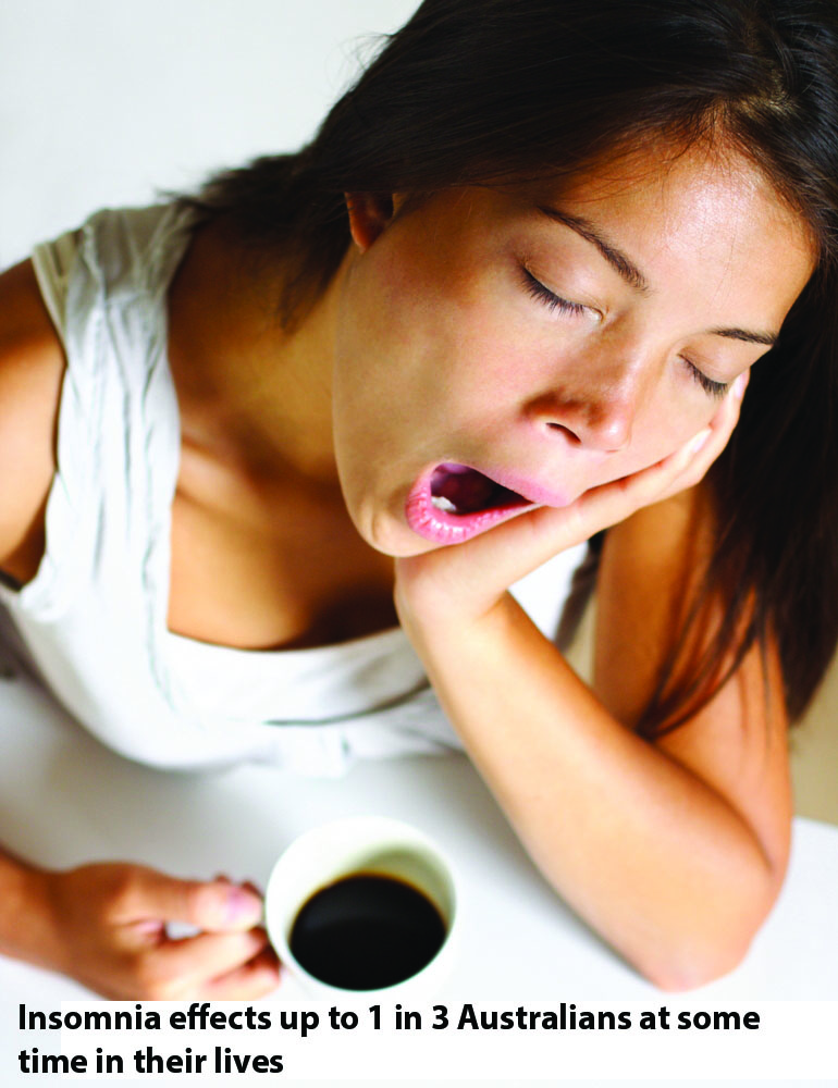 Woman yawning with a cup of coffee in hand
