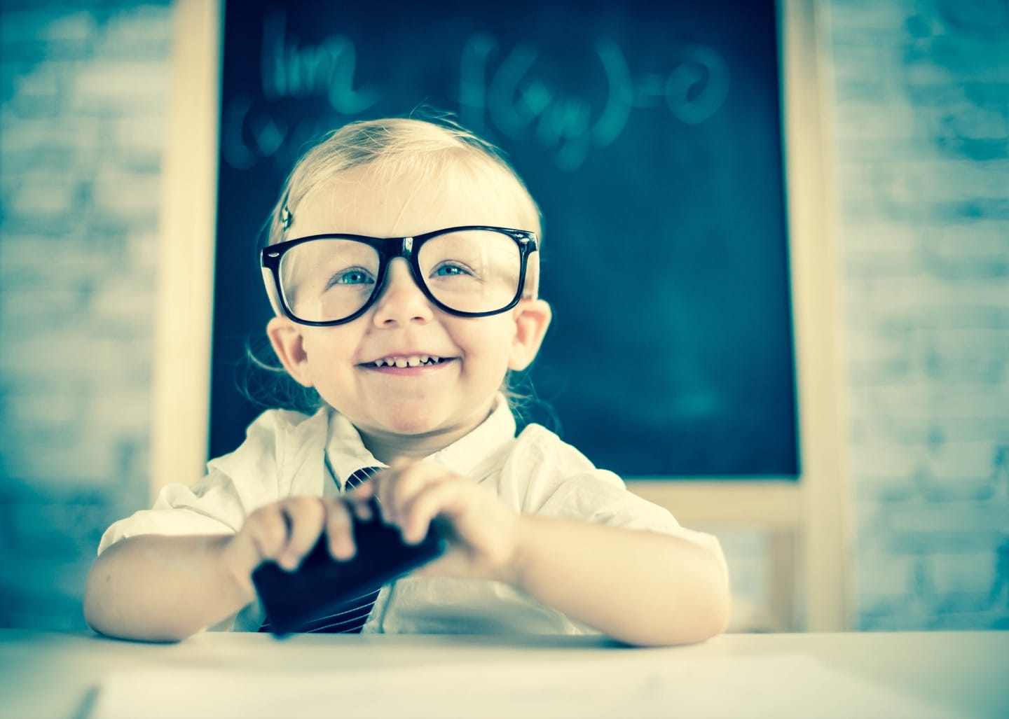 Child genius sat at desk in shcool with glasses on looking very intelligent  - Your Health