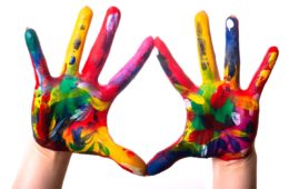 Rainbow coloured hands held up in front of a white background