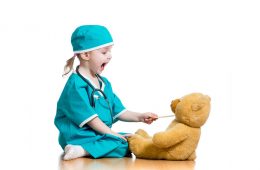 Child pracitcing safely feeding medicine to her teddy bear