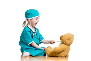 Child pracitcing safely feeding medicine to her teddy bear