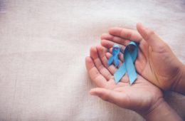Hands holding sky blue ribbons for prostate cancer awareness