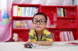 boy with eyeglasses in front of bookshelf