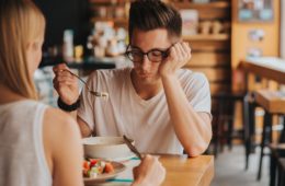Unhappy man with eating problem staring at food in cafe