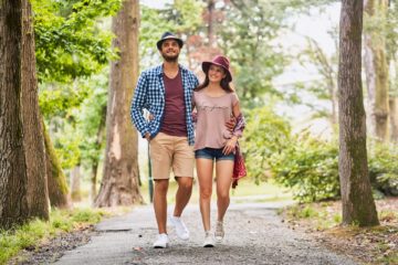 Young couple walking on pathway through grass field