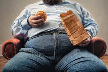 overweight man eating burger