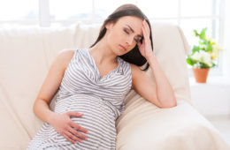 picture of pregnant woman holding head on sofa