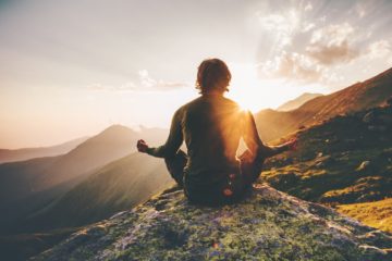 Man meditating at sunset in the mountains