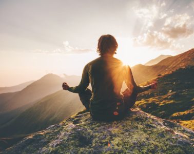 Man meditating at sunset in the mountains