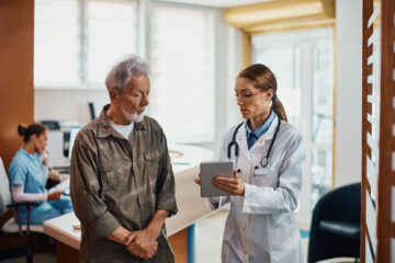 general practitioner and her senior patient using digital tablet